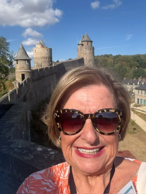 Marsha smiling at the castle walls of Fougères